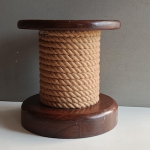 May include: A handcrafted, wooden spool-shaped cat scratching post. The base and top are dark brown, and the central cylinder is wrapped with thick, natural-colored rope. This sturdy, decorative piece provides a scratching surface for cats.