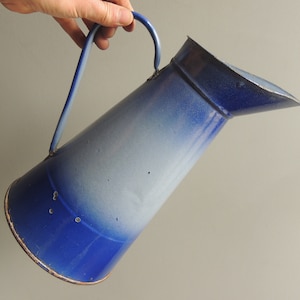 Könnte beinhalten: Eine blaue und weiße Emaille-Kanne mit Henkel. Die Kanne hat einen Farbverlauf, der unten mit einem dunkleren Blau beginnt und oben in Weiß ausläuft.