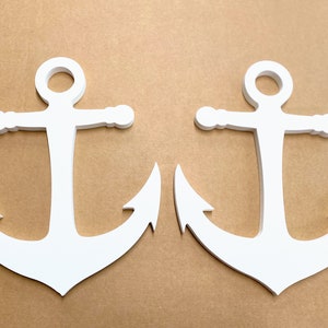 May include: Two white wooden anchors on a brown background. The anchors are identical and have a classic design.