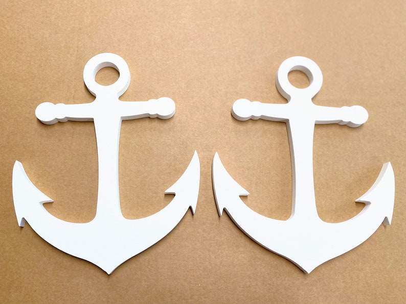 May include: Two white wooden anchors on a brown background. The anchors are identical and have a classic design.