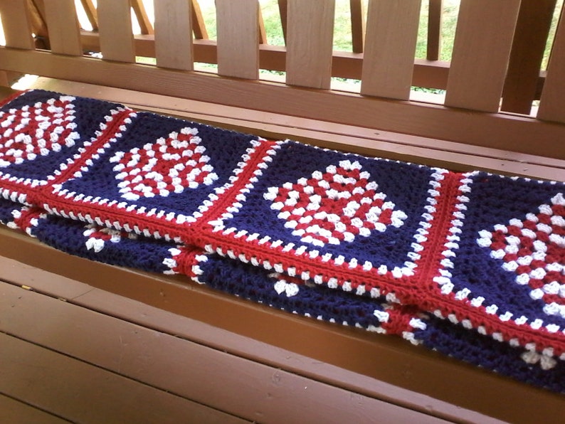 Pu&ograve; includere: Una coperta all'uncinetto con quadrati rossi, bianchi e blu. La coperta &egrave; realizzata in filato e ha un motivo a quadrato della nonna.