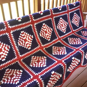 Pu&ograve; includere: Una coperta all'uncinetto in rosso, bianco e blu con un motivo a rombi. La coperta &egrave; realizzata in filato ed &egrave; perfetta per un divano o un letto.