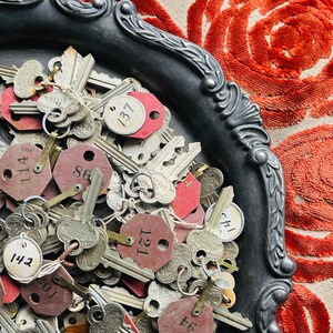 May include: A silver tray filled with a collection of vintage keys and key tags. The tags are numbered and some have the word "Corbin" printed on them.