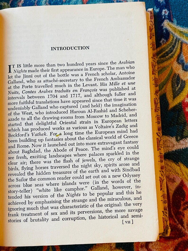 May include: Open book with the title "INTRODUCTION" at the top of the page. The text describes the history of the Arabian Nights. The book has yellowed pages and a decorative gold border.