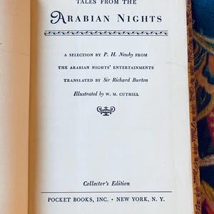 May include: Open book with the title "Tales From The Arabian Nights" in a decorative font. The text includes the author's name, translator, and illustrator. The book is a Collector's Edition published by Pocket Books, Inc., New York, N.Y.