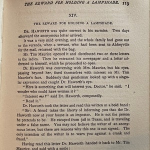 May include: A black and white book with the title "The Reward for Holding a Lampshade" and the chapter title "XIV. The Reward for Holding a Lampshade". The text is from a novel and describes a scene where a doctor receives an anonymous letter.