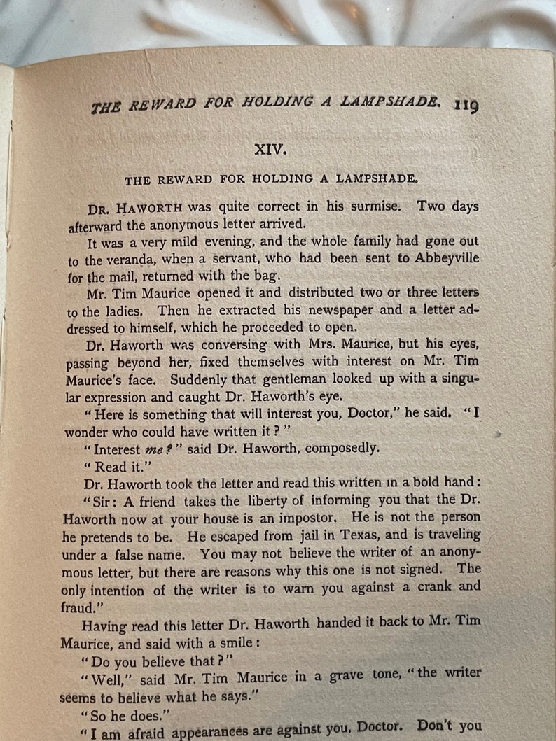 May include: A black and white book with the title "The Reward for Holding a Lampshade" and the chapter title "XIV. The Reward for Holding a Lampshade". The text is from a novel and describes a scene where a doctor receives an anonymous letter.
