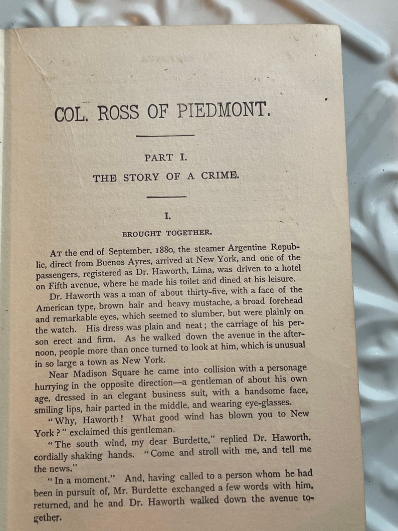 May include: A black and white image of a page from a book. The text on the page is about a man named Dr. Haworth who arrived in New York on a ship from Buenos Aires. The text describes Dr. Haworth's appearance and mentions that he was met by a man named Burdette.