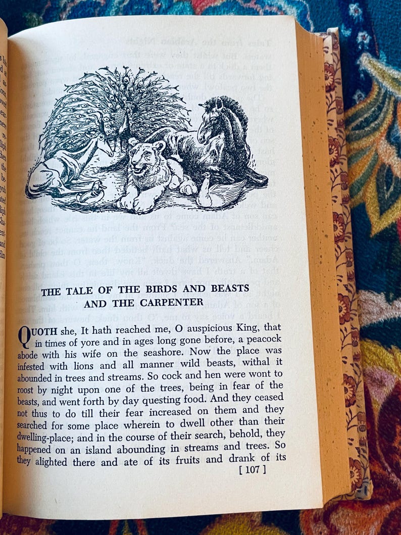 May include: Open book with a black and white illustration of a peacock, lion, horse, and other animals. The text "THE TALE OF THE BIRDS AND BEASTS AND THE CARPENTER" is above the illustration. The page is yellowed.