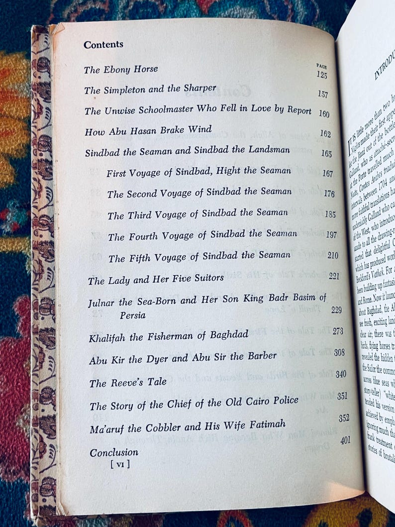 May include: Open book with a contents page featuring a list of stories, including "Sindbad the Seaman" and "The Ebony Horse." The page numbers are listed on the right side. The book's edges are aged with a decorative border.
