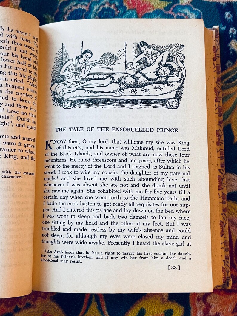 May include: An open book with text and a black and white illustration of a man reclining on a bed with two women. The text reads "THE TALE OF THE ENSORCELLED PRINCE".