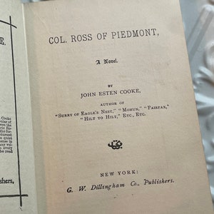 May include: A vintage book cover with the title "Col. Ross of Piedmont" by John Esten Cooke. The book is a novel and was published by G.W. Dillingham Co. in New York.