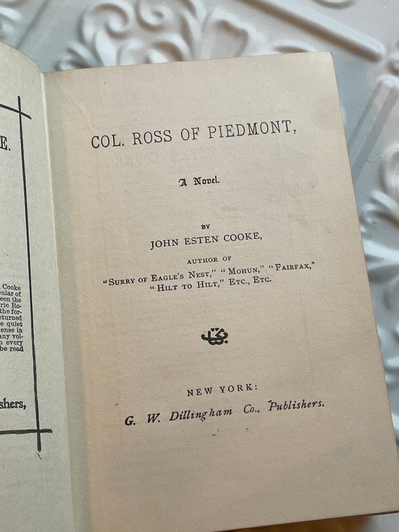 May include: A vintage book cover with the title "Col. Ross of Piedmont" by John Esten Cooke. The book is a novel and was published by G.W. Dillingham Co. in New York.