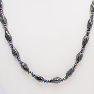 May include: A black necklace with faceted, oval-shaped hematite beads and smaller iridescent round beads.