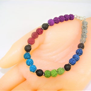 May include: A rainbow colored lava rock bracelet with silver beads. The bracelet is made of small, round beads in shades of purple, red, blue, green, and black.