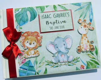 May include: A green and white scrapbook with a red ribbon. The cover features a jungle theme with a lion, elephant, and giraffe. The text on the cover reads "Isaac Gabriel's Baptism 3rd June 2018".