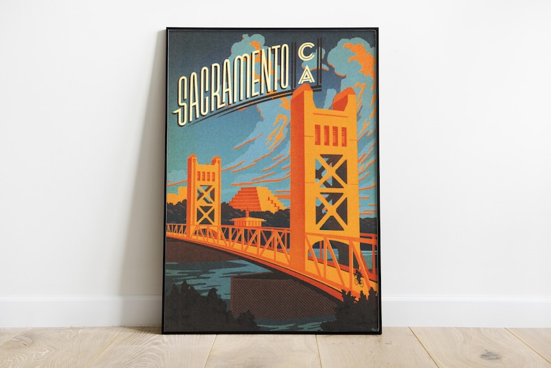 May include: A vintage-style poster featuring a stylised illustration of the Tower Bridge in Sacramento, California. The poster is in a black frame and has a blue, orange, and yellow colour scheme. The text "Sacramento CA" is written in a stylised font at the top of the poster.