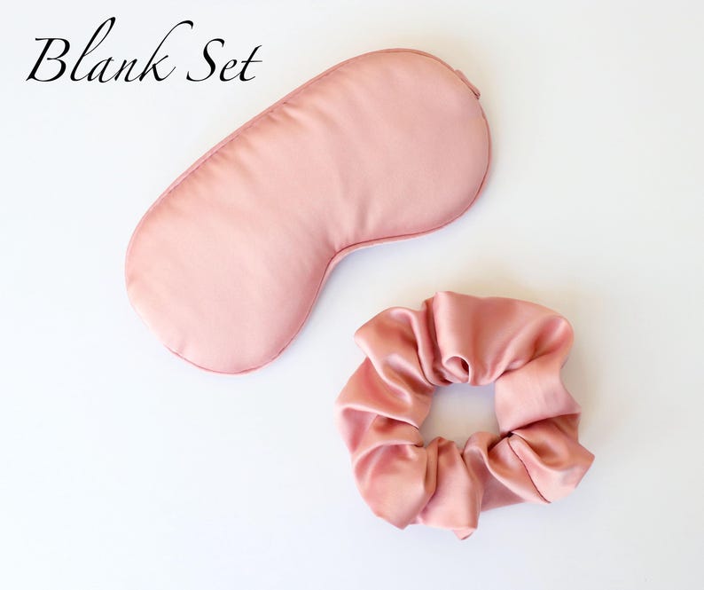 May include: A blush pink sleep set featuring a satin eye mask and a matching scrunchie. The eye mask is contoured for comfort. The scrunchie is gathered and made of the same satin material. The words "Blank Set" are in the upper left corner.