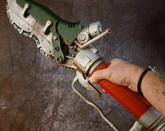 May include: A green and silver chainsaw-like weapon with a red handle. The weapon has a chain and a metal blade.