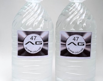 Op de afbeelding: Twee grote, transparante plastic flessen gevuld met een heldere vloeistof. Elke fles heeft een wit etiket met de tekst "47 AG 20 PPM COLLOID". De flessen hebben witte handvatten en doppen. Witte achtergrond.