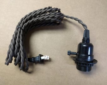May include: A black pendant light fixture with a twisted gray and black fabric-covered cord. The cord is coiled and connected to a black plug. The light socket is black.