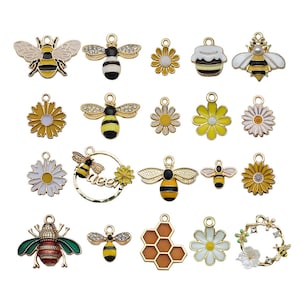 Könnte beinhalten: Sortiment von 19 goldfarbenen Bienen- und Blumenanhängern. Die Anhänger zeigen gelbe und schwarze Bienen, gelbe Blumen und ein Wabenmuster. Die Anhänger sind perfekt für die Schmuckherstellung, das Scrapbooking und andere Bastelarbeiten.