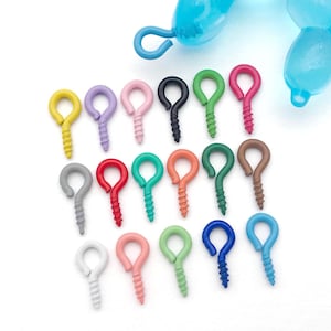 May include: A collection of colorful screw eye hooks in various colors, including yellow, purple, pink, black, green, red, gray, teal, orange, brown, white, and blue. The hooks are arranged on a white surface.