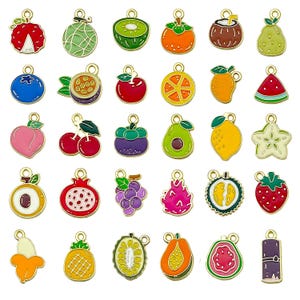 Può includere: Una collezione di ciondoli colorati a forma di frutta con anelli in metallo dorato. I ciondoli includono fragole, kiwi, arance, mirtilli, pesche, ciliegie, uva e altro. Ogni ciondolo è smaltato con colori vivaci e disegni dettagliati.