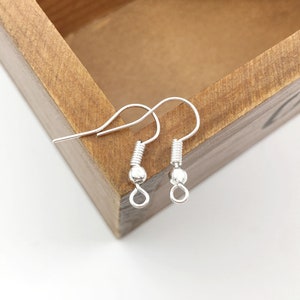 May include: Two silver earring hooks with a small ball at the end of each hook.