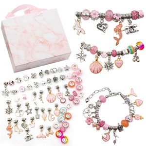 May include: A set of pink and silver charm bracelets with a variety of charms, including a unicorn, mermaid, camera, seashell, snowflake, and crown. The charms are packaged in a pink and white box.