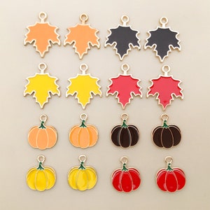 May include: Assortment of metal charms in the shape of maple leaves and pumpkins. The charms are in various colors, including orange, yellow, red, black, and brown. The charms are perfect for adding a touch of fall to your jewelry or crafts.