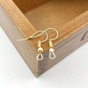 May include: Two gold-toned earring hooks with a small ball at the top of each hook.