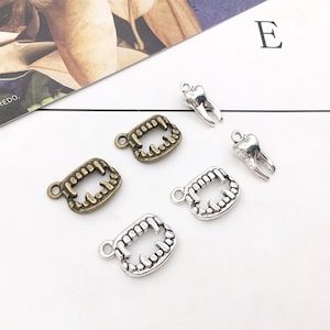 May include: A set of six silver and bronze charms featuring teeth and fangs. The charms are perfect for jewelry making or adding a spooky touch to crafts.