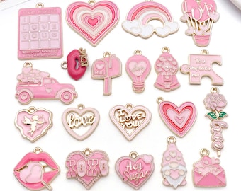May include: A collection of pink enamel charms with gold-colored accents. The charms feature various Valentine's Day and love-themed designs, including hearts, a rainbow, a gumball machine, and the text "LOVE".