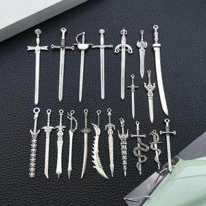 Könnte beinhalten: Eine Sammlung von siebzehn schwertförmigen Anhängern aus silberfarbenem Metall, angeordnet in zwei Reihen. Jeder Anhänger weist eine einzigartige Klingenform, ein Griffdesign und Knaufdetails auf, darunter gerade, geschwungene und gezackte Klingen.