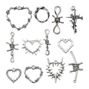 May include: A set of 12 silver-toned metal charms featuring various designs, including hearts, crosses, and circles. The charms are made of barbed wire and have a rustic, edgy aesthetic.