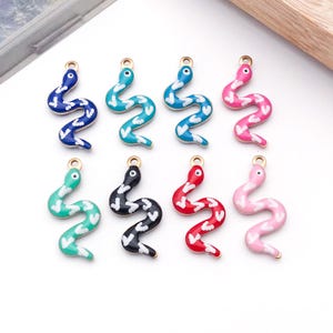 May include: Eight metal snake charms arranged in two rows, each featuring a different solid colour enamel finish including dark blue, teal, light blue, hot pink, mint green, black, red, and light pink, all with white heart-shaped patterns.