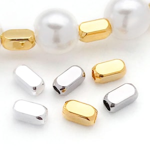 May include: A close-up of six metal bead caps for jewelry making. Three are gold and three are silver. The caps are oval shaped and have a smooth, polished finish.