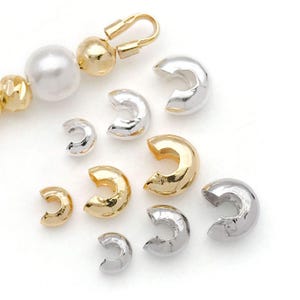 Könnte beinhalten: Sortiment an Gold- und Silber-Crimpperlen in verschiedenen Größen. Diese Perlen werden verwendet, um die Enden von Schmuckschnüren und -ketten zu sichern.