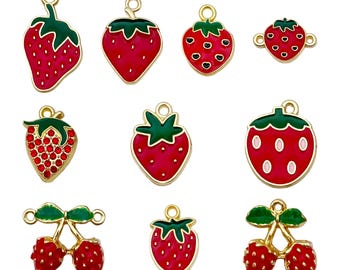 Puede incluir: Una colección de dijes con temática de fresas en varios diseños. Los dijes presentan fresas de esmalte rojo con hojas verdes y detalles metálicos dorados. Algunos dijes tienen un diseño de pedrería.