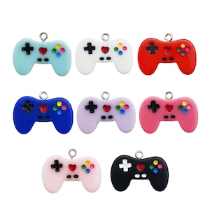 May include: Ten colorful plastic game controller charms with a heart and button details. The charms are in various colors including blue, red, pink, purple, white, and black.