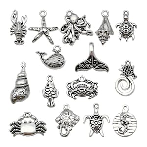May include: A set of 15 silver-toned metal charms featuring various sea creatures and nautical designs. The charms include a starfish, an octopus, a seashell, a turtle, a whale, a crab, a fish, a seahorse, a stingray, and a mermaid.
