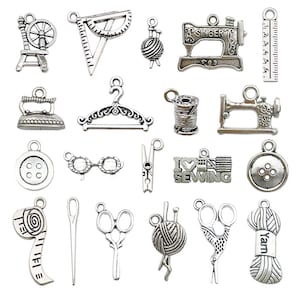 Könnte beinhalten: Eine Sammlung silberfarbener Näh-Charms, darunter ein Spinnrad, ein Lineal, ein Garnknäuel, eine Singer-Nähmaschine, ein Bügeleisen, ein Kleiderbügel, eine Garnspule, ein Knopf, eine Brille, eine Wäscheklammer und eine Schere. Ideal für Schmuckherstellung.