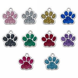 以下が含まれることがあります： 足跡の形をしたペットIDタグ10個のコレクション。各タグはシルバーの縁取りがあり、ピンク、シルバー、ゴールド、ブルー、ブラック、グリーン、レッド、パープル、ティールなど、さまざまな色のキラキラした足跡が付いています。