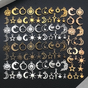 May include: A selection of celestial charms in gold, silver, and bronze tones. The charms feature suns, moons, stars, and hearts. The charms have detailed designs and come in different sizes. These charms are suitable for jewellery making and other craft projects.