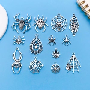 Peut inclure: Un ensemble de 14 breloques en argenté en forme d'araignée et de toile d'araignée. Les breloques sont parfaites pour la fabrication de bijoux, le scrapbooking et d'autres projets d'artisanat.