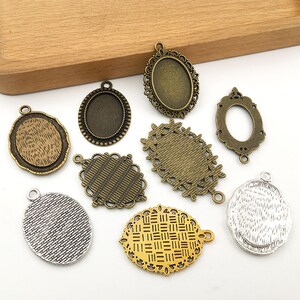 May include: Assortment of eight metal pendant trays in various shapes and sizes. The trays are in gold, silver, and bronze tones. Some trays have a textured surface, while others have a smooth surface. The trays are perfect for creating custom jewelry.