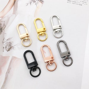 May include: Six metal keychains in different finishes: gold, silver, rose gold, and black. Each keychain has a swivel clasp and a loop for attaching keys or other items.