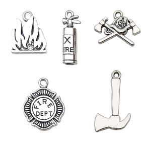 Op de afbeelding: Zes zilveren bedels met een brandweerthema. De bedels omvatten een brandblusser, een brandweerbijl, een brandweerbadge, een brandkraan, een brandweerwagen en een brandweerhelm.