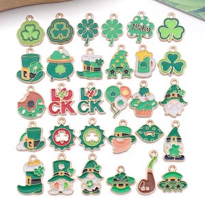Könnte beinhalten: Eine Sammlung von St. Patrick's Day-Anhängern in Grün und Gold. Die Anhänger zeigen Kleeblätter, Leprechaun-Hüte, Goldtöpfe und das Wort "LUCKY". Geeignet für Schmuckherstellung oder Bastelprojekte.